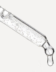 Pipeta con sérum transparente liberando una gota sobre fondo neutro.