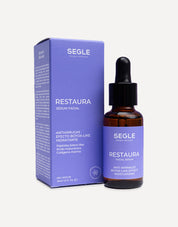 Frasco de sérum con pipeta, envase de vidrio ámbar y etiqueta minimalista sobre fondo de color azul.